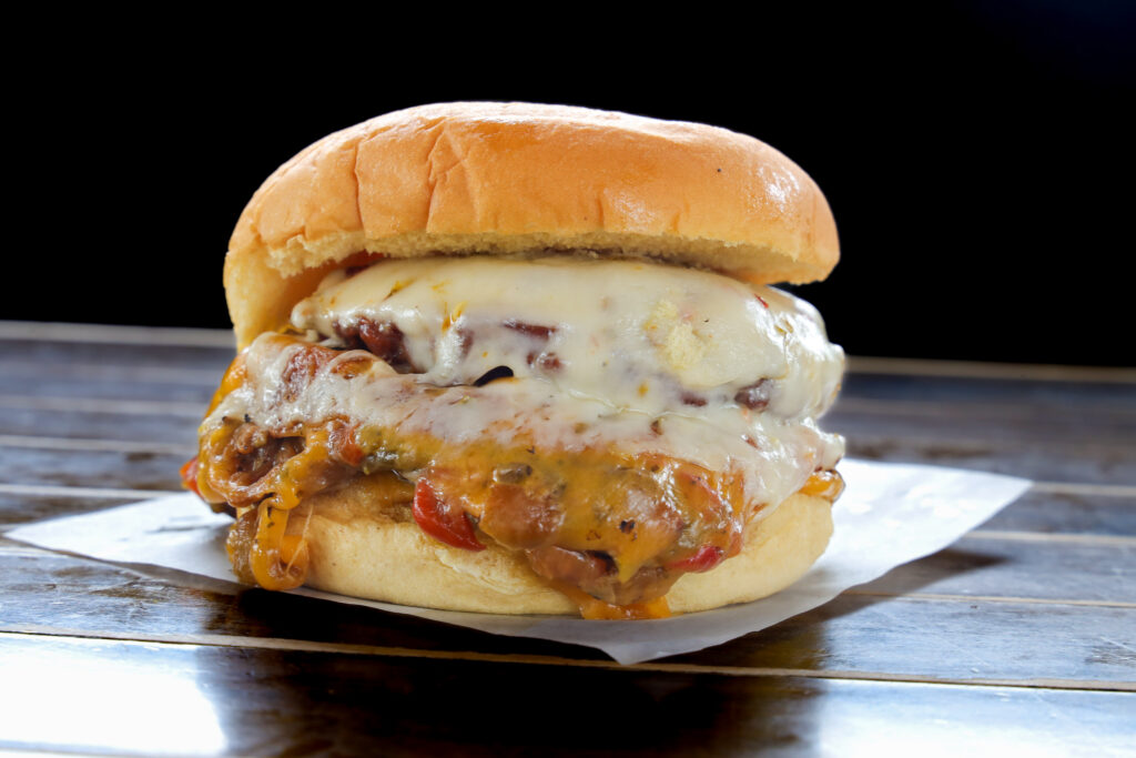 Smash burger with melted cheddar and pepper jack cheese, two latkes, and hatch green chile on a soft potato roll