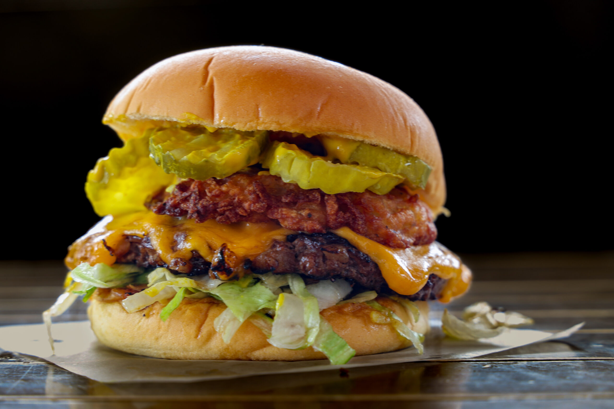 Smash burger with a crispy latke, lettuce, melted cheese, and pickles on a potato roll